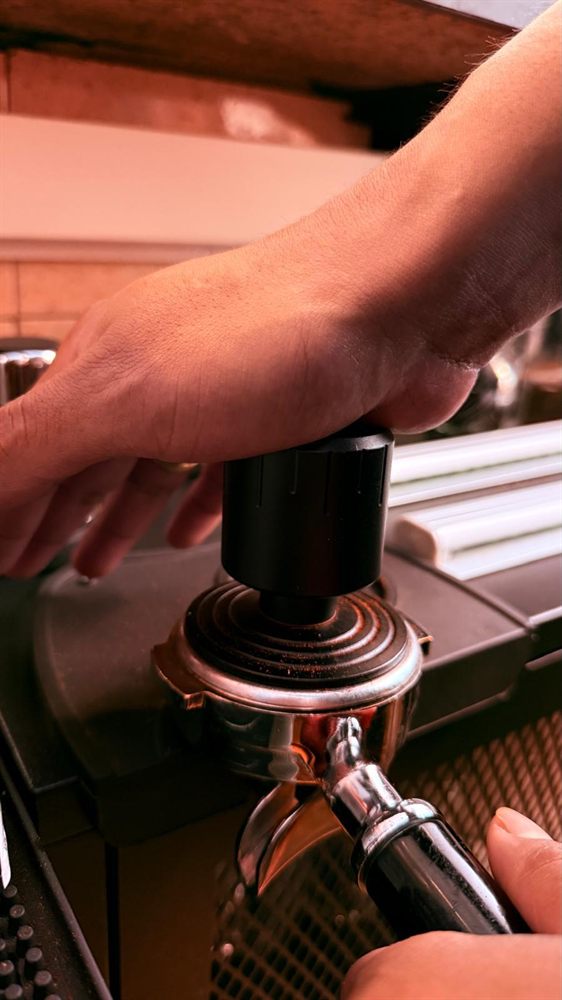 Manos del barista prensando el café en el portafiltro.