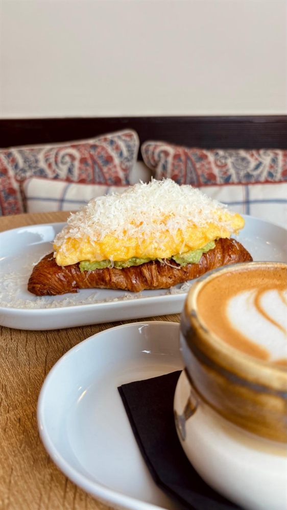 Croissant a la plancha con huevo y un cappuccino, recién servidos.