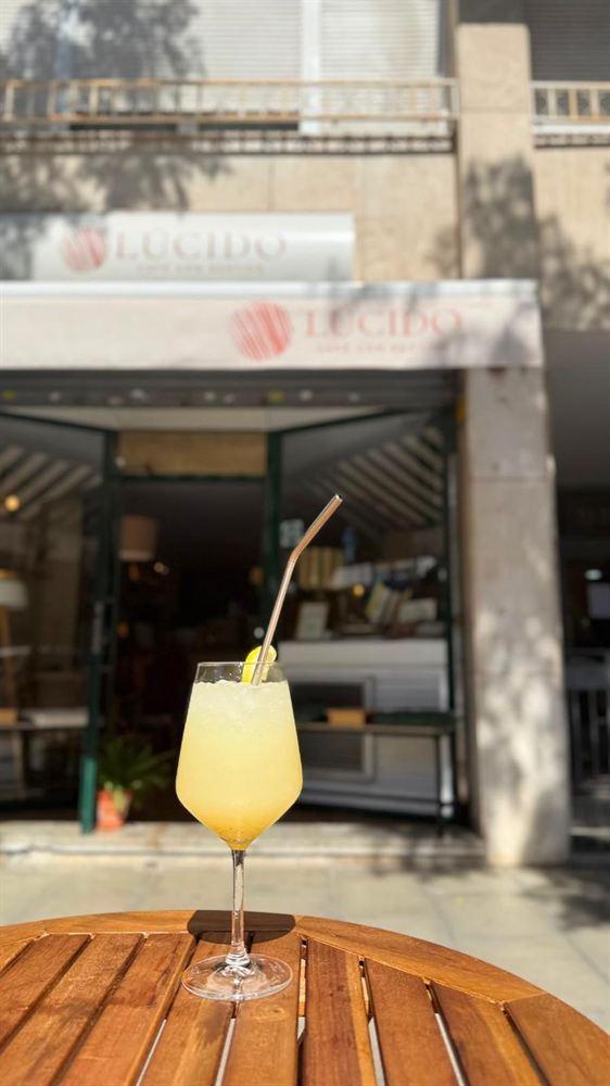 Limonada de la casa en una mesa de la terraza, con la fachada de Lúcido detrás.