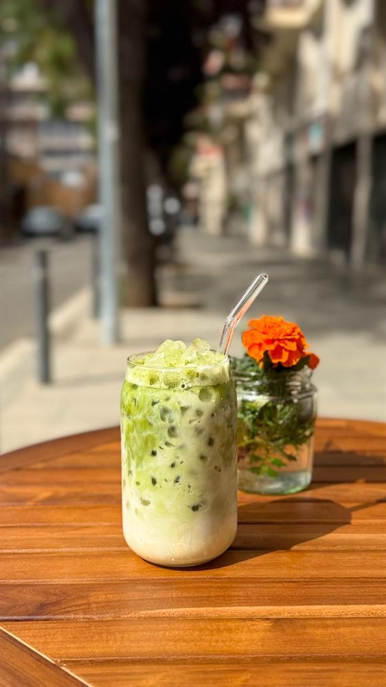 Matcha latte helado con una flor, en una mesa de la terraza.