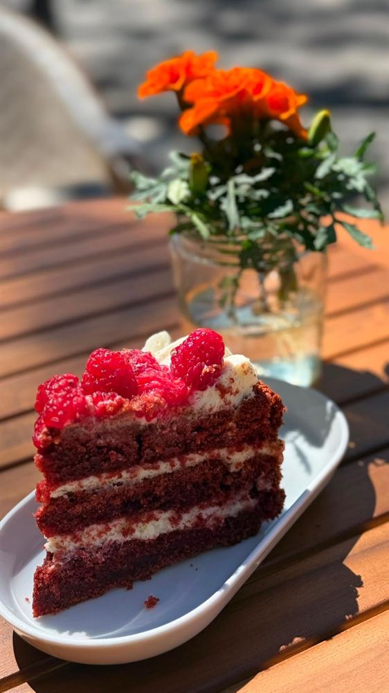 Porción de tarta red velvet con frambuesas frescas.