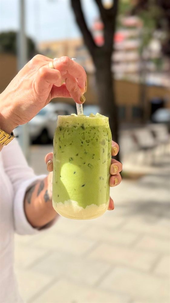 Smoothie verde con pajita, sostenido a la luz de la calle.