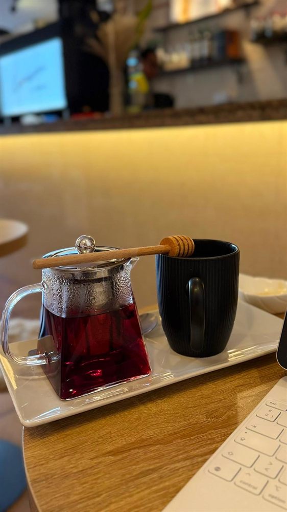 Tetera de cristal con una infusión roja y una taza negra en la barra.
