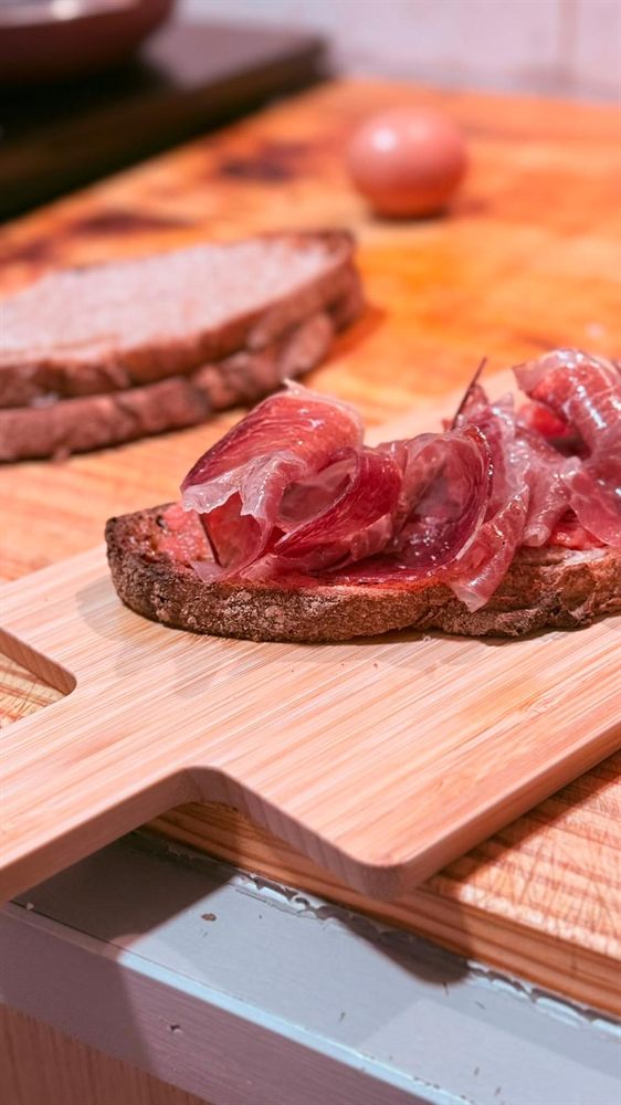 Tostada de pan de obrador con jamón ibérico sobre una tabla.